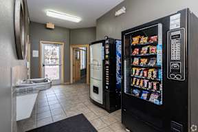 A vending machine sits in a room with a doorway leading to a balcony.