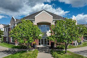 A modern house with a large front yard and trees.