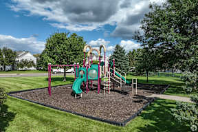 A playground with a green slide and a red and yellow structure.