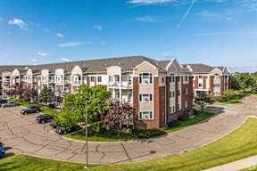 A large apartment complex with a parking lot in front.