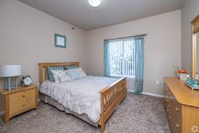 A bedroom with a bed, nightstand, and dresser.