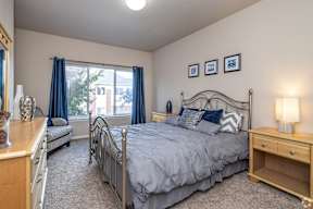 A bedroom with a large bed and a window with blue curtains.