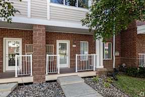 A brick house with a white door and a white railing.