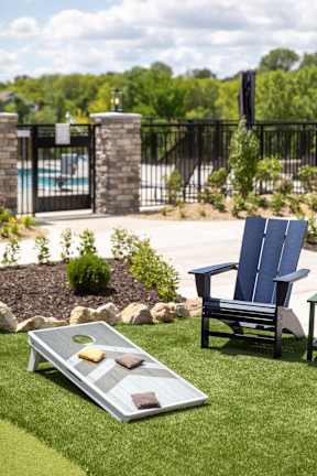 A blue chair is placed on a lawn next to a table with a tray and two blocks.