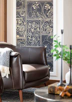 A brown leather chair with a grey throw blanket on it.