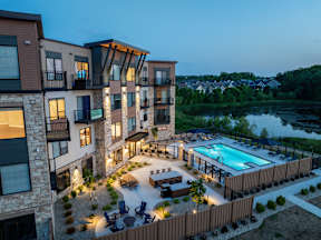 A modern apartment complex with a pool and outdoor seating area.