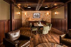 A room with brown leather chairs and a wooden table.