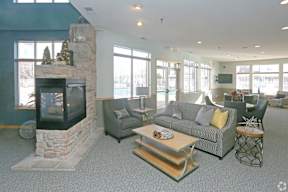 A living room with a stone fireplace and grey couches.