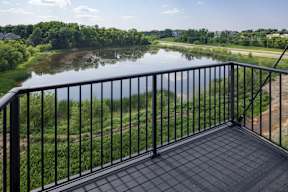 A balcony overlooks a river and greenery.