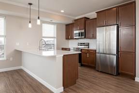A kitchen with a refrigerator, microwave, and cabinets.