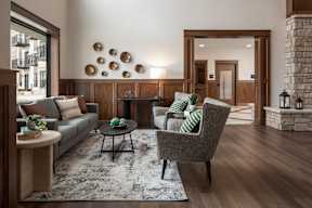 A living room with a grey sofa, a black coffee table, a grey armchair, and a fireplace.