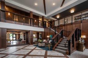 the lobby of a hotel with a staircase and a seating area