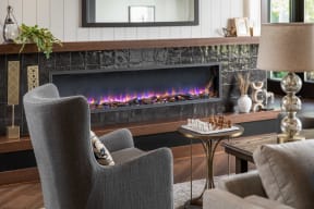 a fireplace in a living room with chairs and a table