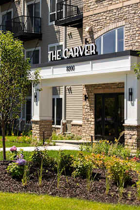 The front of a building called The Carver with a flower bed in front.
