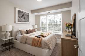 A bedroom with a bed, nightstand, and a painting on the wall.