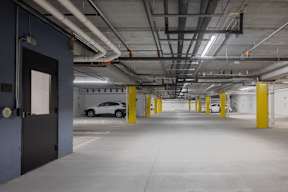 A car is parked in a parking garage with yellow poles.