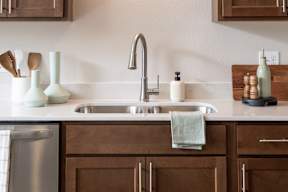 A kitchen with brown cabinets and a white sink.