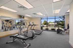 a fitness room with exercise equipment and a large window