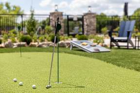 A miniature golf course with a green putting mat, a ball, and a putter.