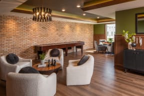 a living room with a brick wall and chairs and a table