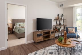 a living room with a tv and a bedroom in the background