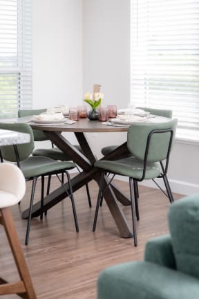a dining room with a wooden table and green chairs