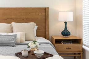 a bedroom with a bed with a wooden headboard and a table with a lamp