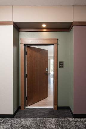A hallway with a brown door and a sign on the wall.