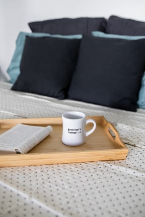 a tray with a cup of coffee and a bible on a bed