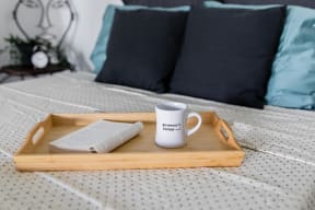 a tray with a book and a mug on a bed