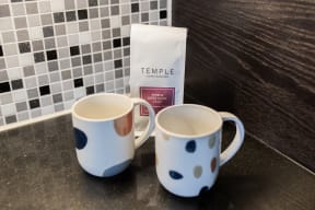 two mugs and a bag of temple coffee on a table