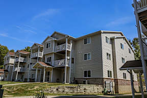 A large apartment building with multiple balconies and a clear blue sky above.