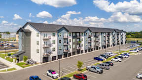 A parking lot in front of a multi-story apartment building.