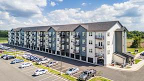 A large apartment complex with a parking lot in front.