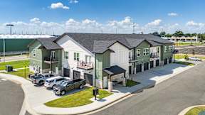 A row of houses with cars parked in front.