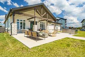 A house with a covered patio and lawn chairs.