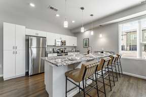 A modern kitchen with a marble countertop and stainless steel appliances.