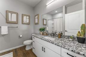 A bathroom with a toilet, sink, and mirror.