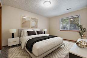 A bedroom with a large bed, two lamps, and a painting on the wall.