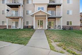 Apartment building with a front lawn and a walkway leading to the entrance.