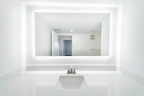 A white sink in a bathroom with a mirror above it.
