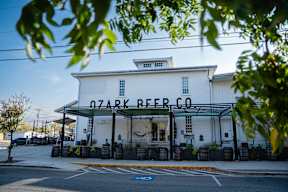 A white building with a black awning that says Ozark Beer Co.