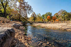 A stream flows through a rocky landscape with trees in autumn colors.