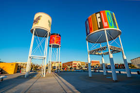 Two water towers with the word "FLOW" on them stand in a parking lot.