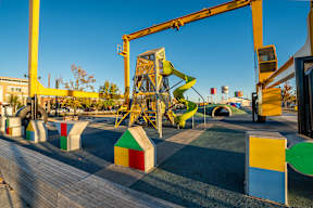 A playground with a yellow crane-like structure and a green slide.