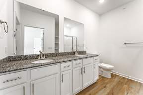 A bathroom with a granite countertop and white cabinets.