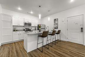 A kitchen with white cabinets and a wooden floor.