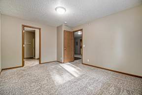 A room with a carpeted floor and two doors.