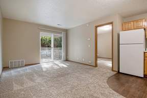 A spacious living room with a white refrigerator on the right side.