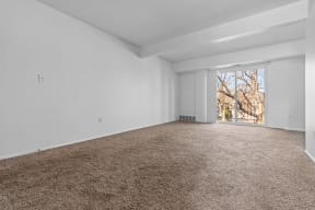 a living room with white walls and carpet and a window